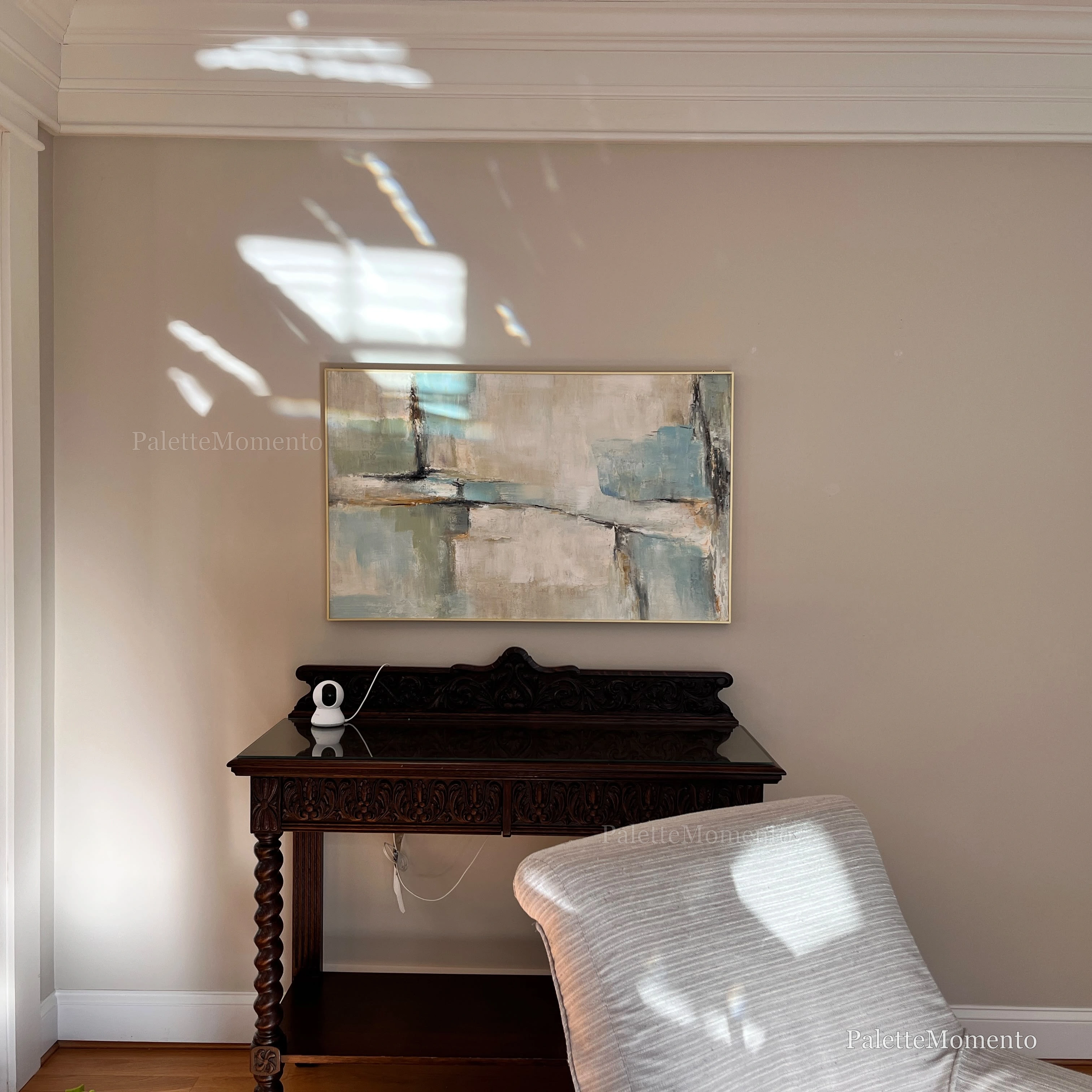 Client's own photograph of the framed blue and sage abstract oil painting above a dark carved table at home
