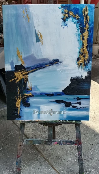Blue white black and gold-colored abstract painting on a paint-marked studio easel