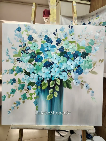 Blue and teal floral painting displayed on a wooden studio easel