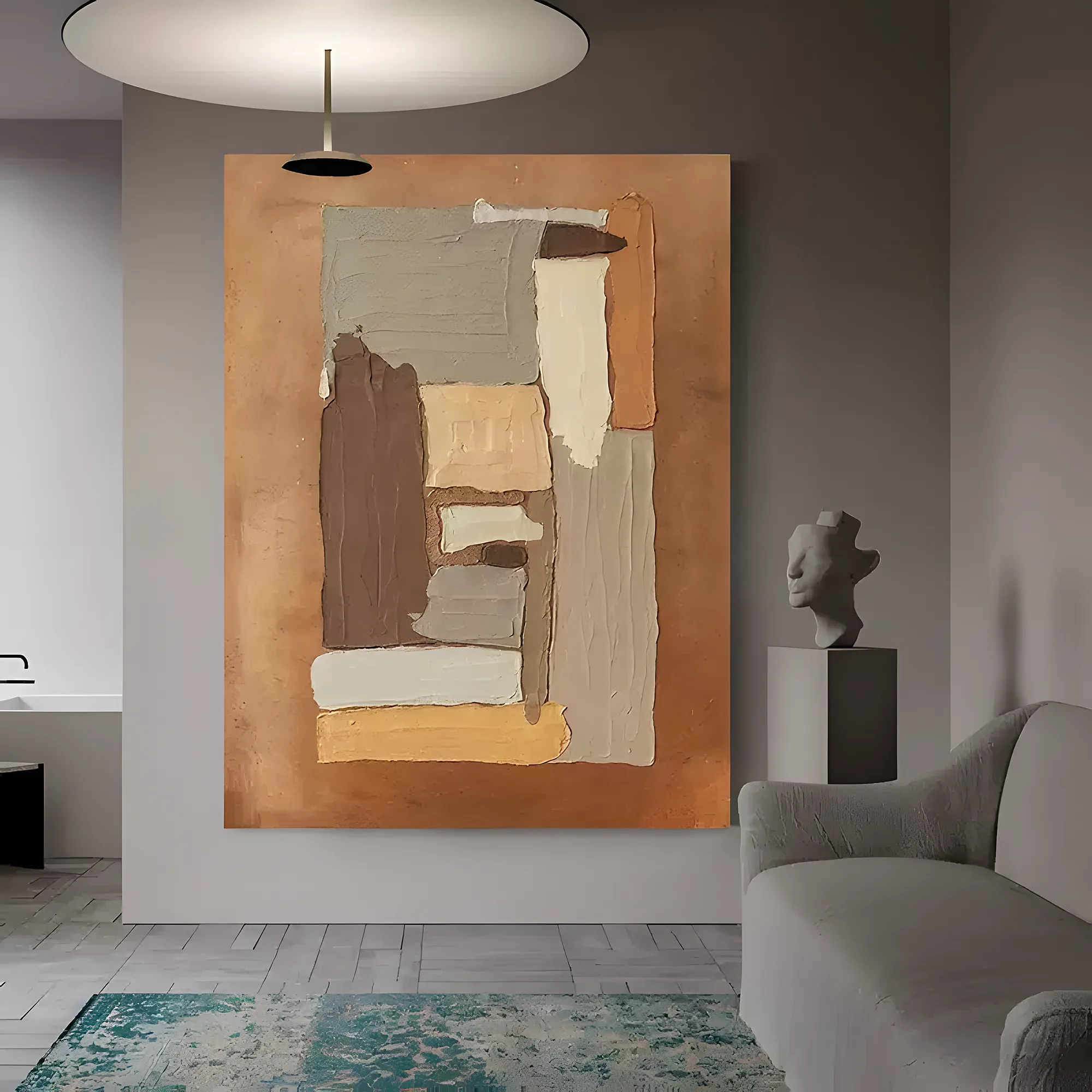 Wabi-sabi canvas of stacked tan, gray, and chocolate thick paint patches on a burnt caramel field, hung on a pale gray wall near a stone bust on a plinth, a gray boucle sofa, and a faded teal rug
