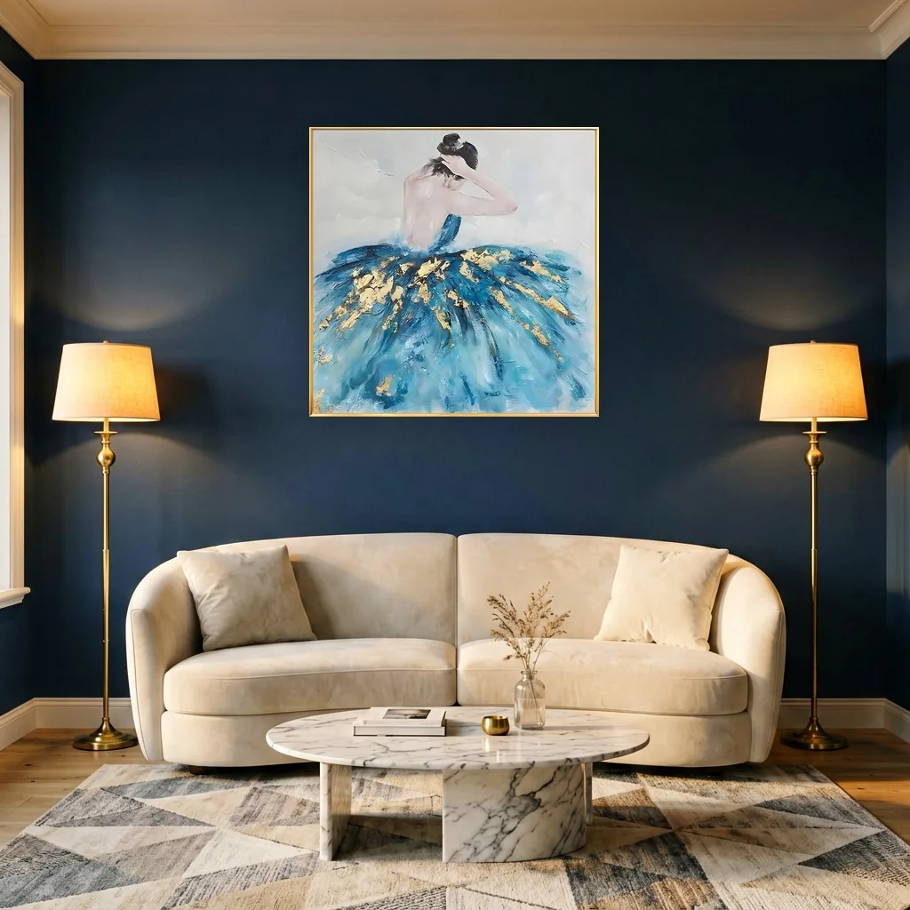 Gold-framed canvas painting of a ballet dancer seen from behind, her deep blue tutu flecked with gold leaf, centered on a navy wall between two lit brass floor lamps above a curved cream sofa and marble table