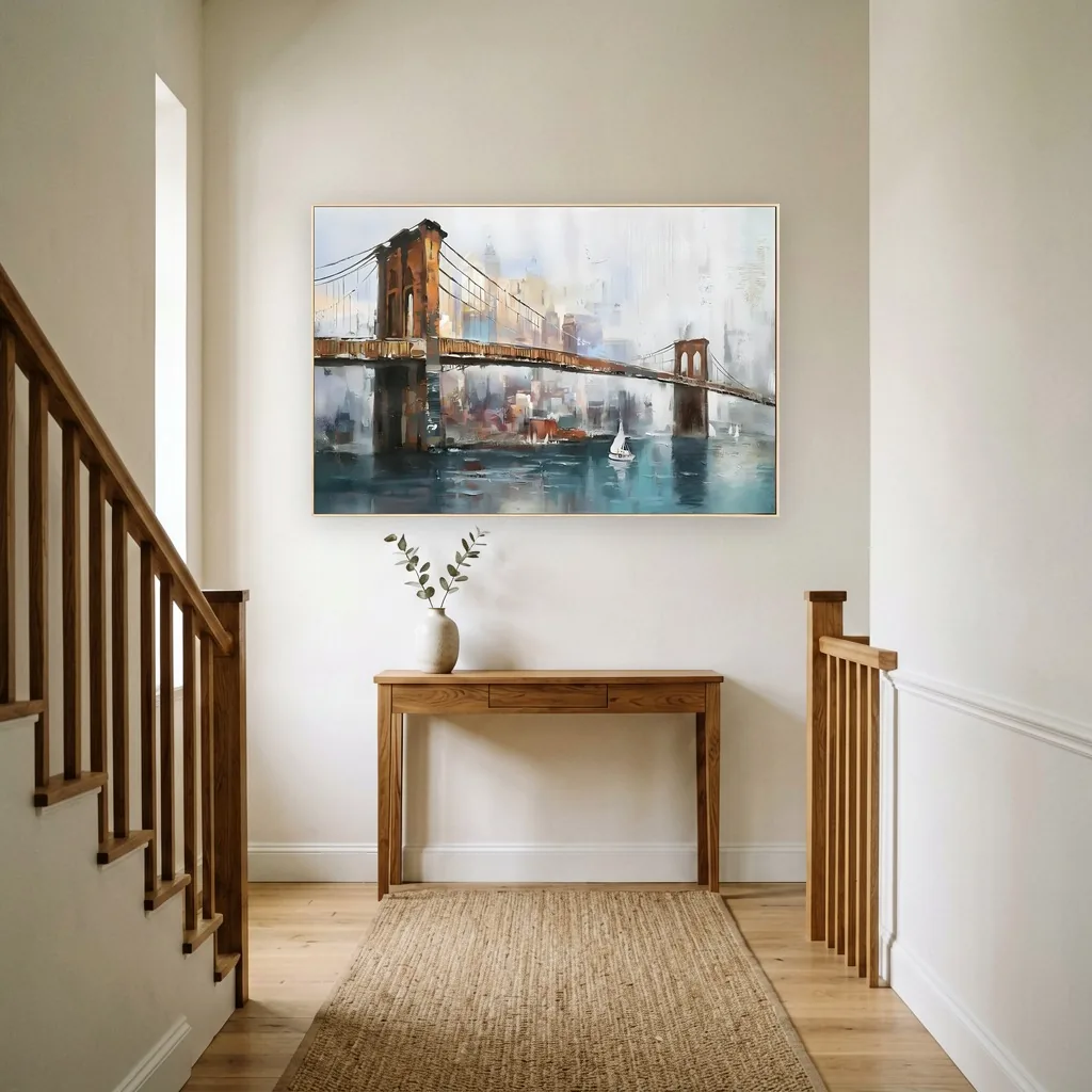 Painting of the Brooklyn Bridge over teal harbor water with a small white sailboat, hung above an oak console table in a stairway hall