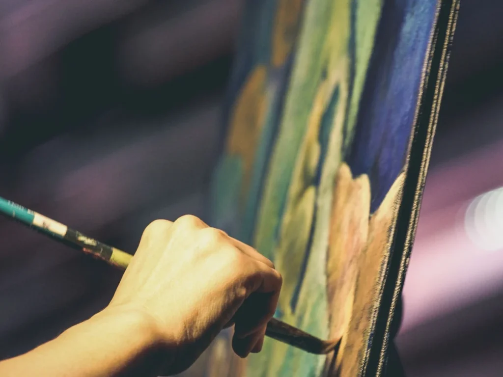 Artist's hand painting details onto a stretched canvas
