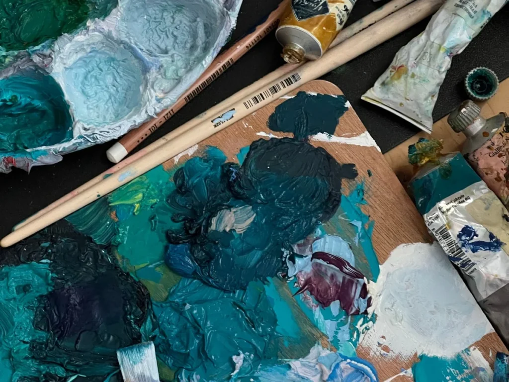 Wooden palette loaded with oil paints mixed for a custom canvas