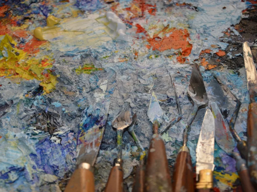 Palette knives coated in thick impasto paint in the studio