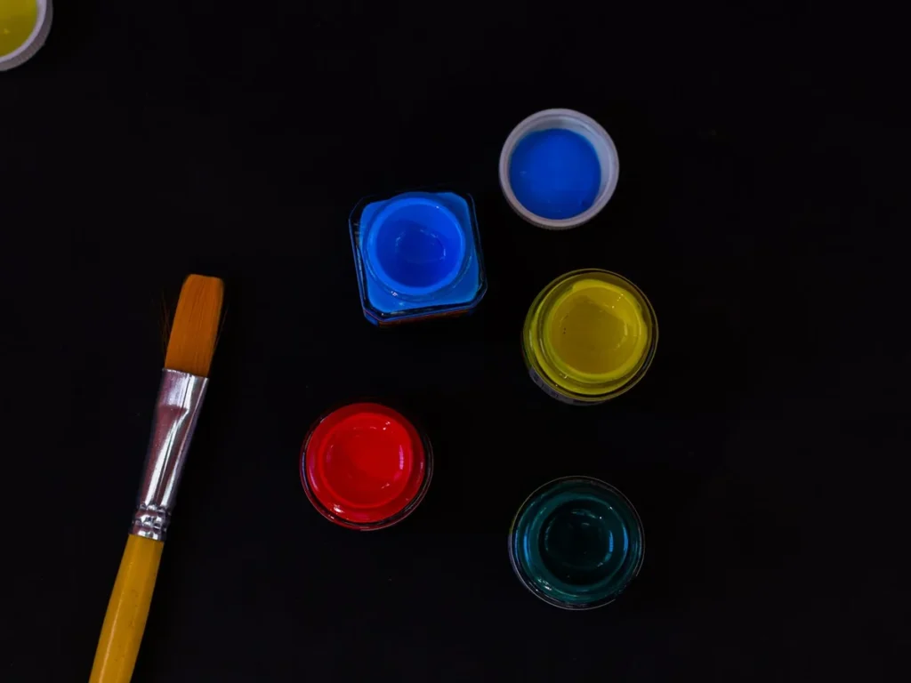 Pots of paint and a brush laid out in the studio