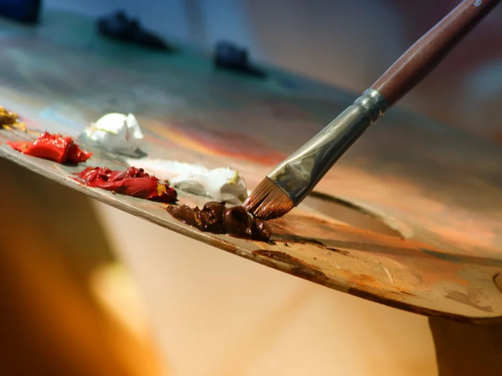 Brush lifting thick oil paint from the artist's palette