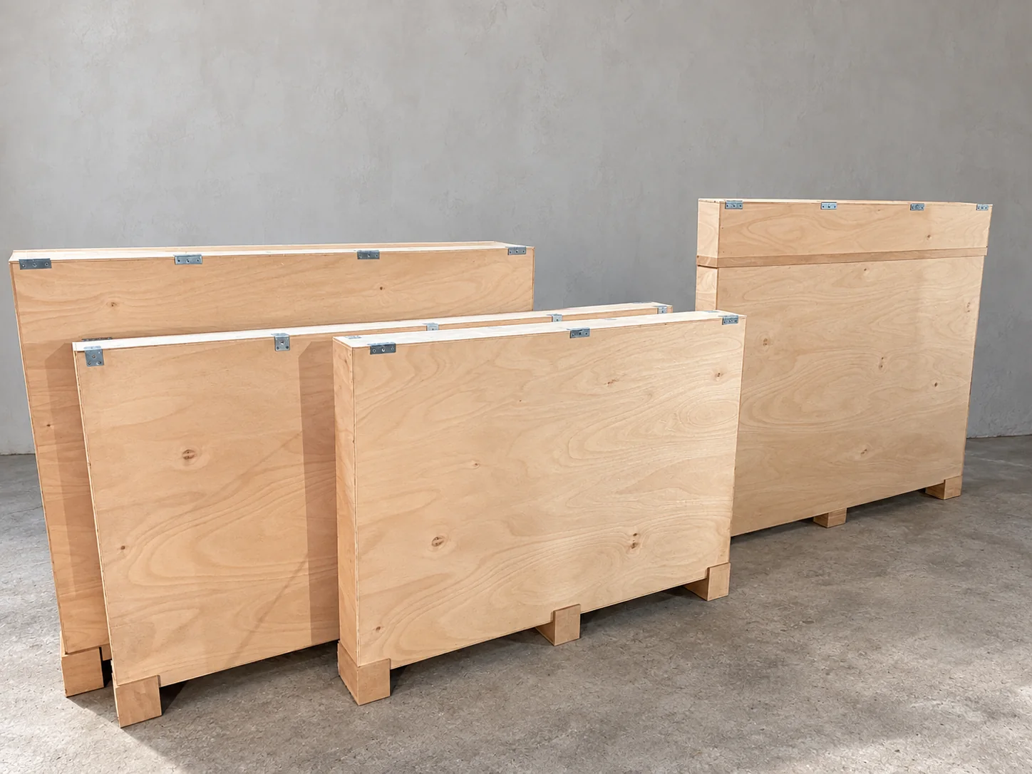 Flat plywood artwork shipping cases in several sizes, with metal fittings and raised protective feet
