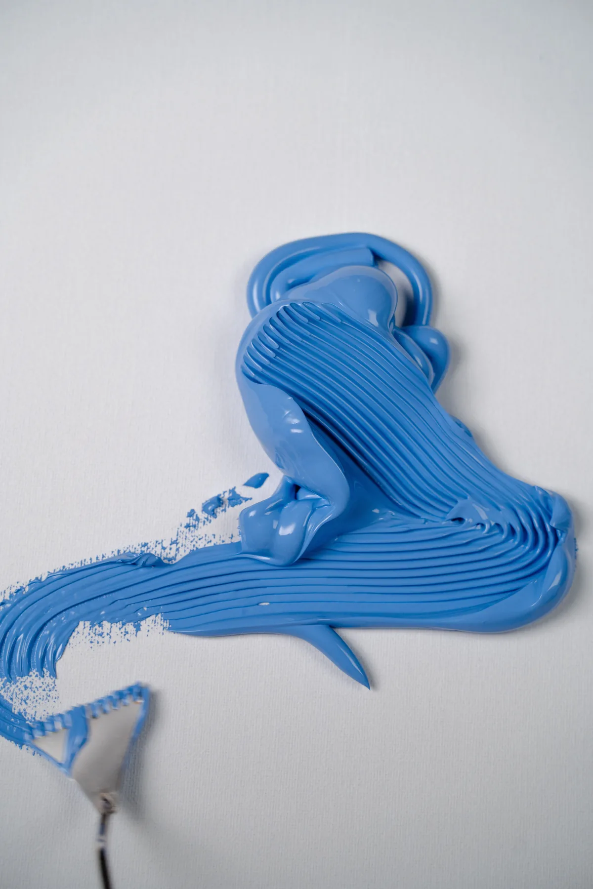 Illustrative stock photograph of blue acrylic paint spread with a palette knife, showing raised ridges of impasto.