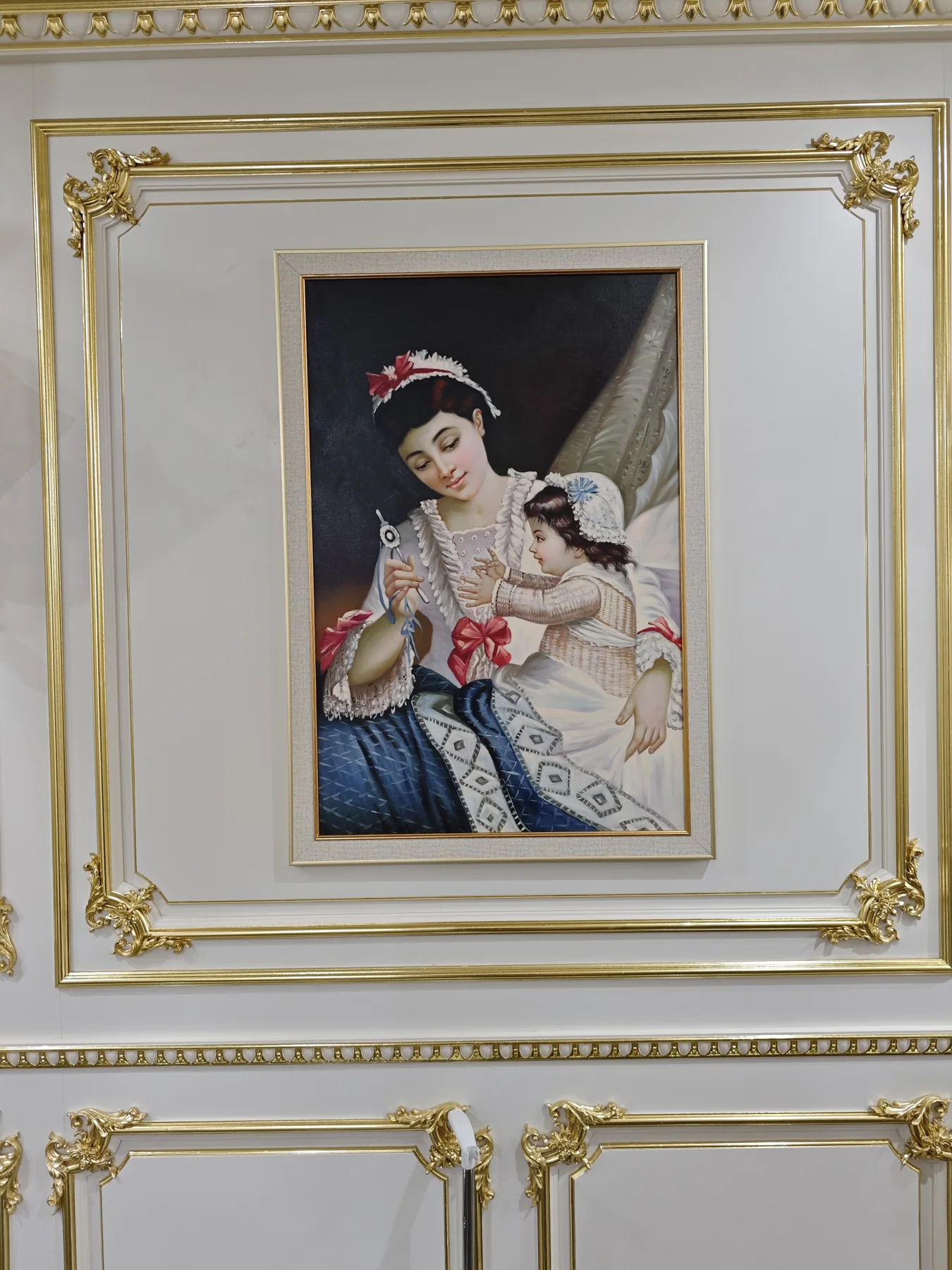 Framed mother-and-child painting set within white and gold wall molding
