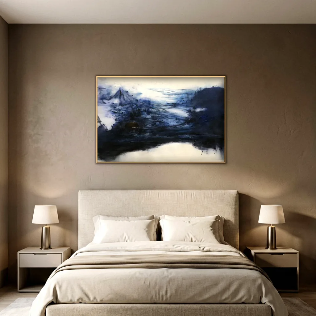 Indigo and cream abstract wall art centered on a warm taupe plaster wall above an oatmeal linen headboard, cream bedding with a taupe throw and two brass lamps on cream nightstands